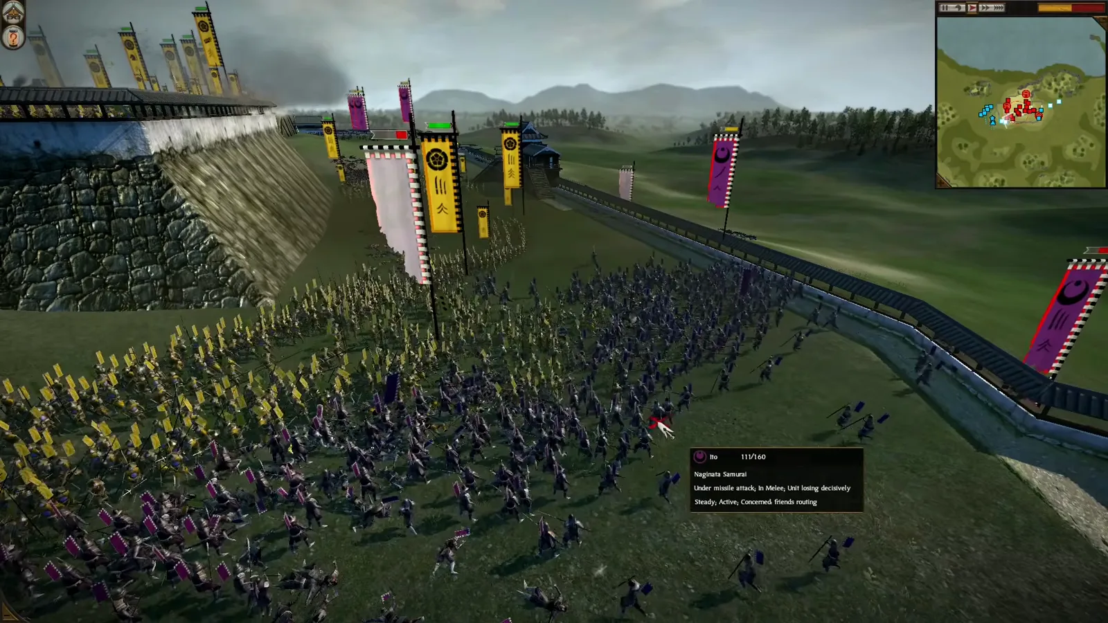 Shogun 2 infantry fight below the inner wall while yellow-bannered archers occupy the higher castle rampart.